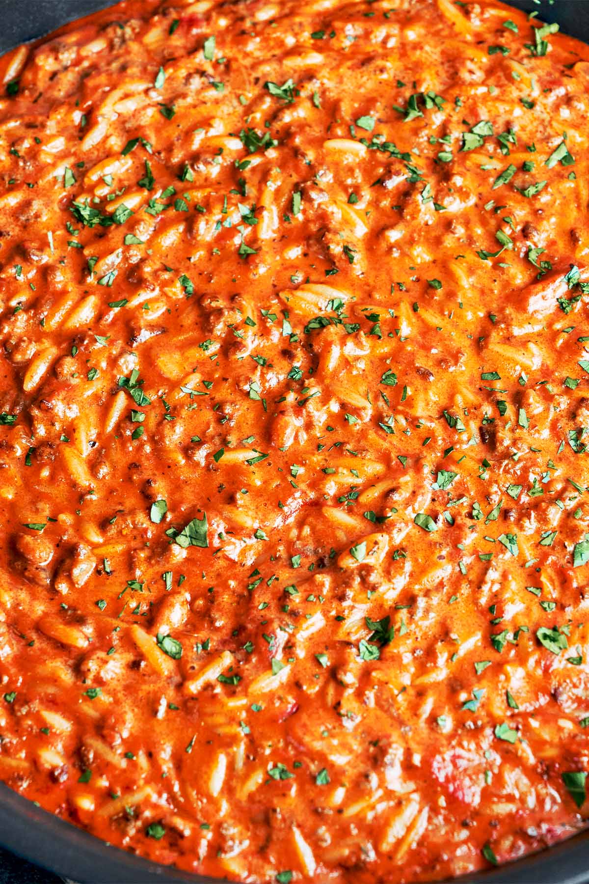 Creamy ground beef orzo finished in a skillet with tomato-cream sauce and fresh parsley.