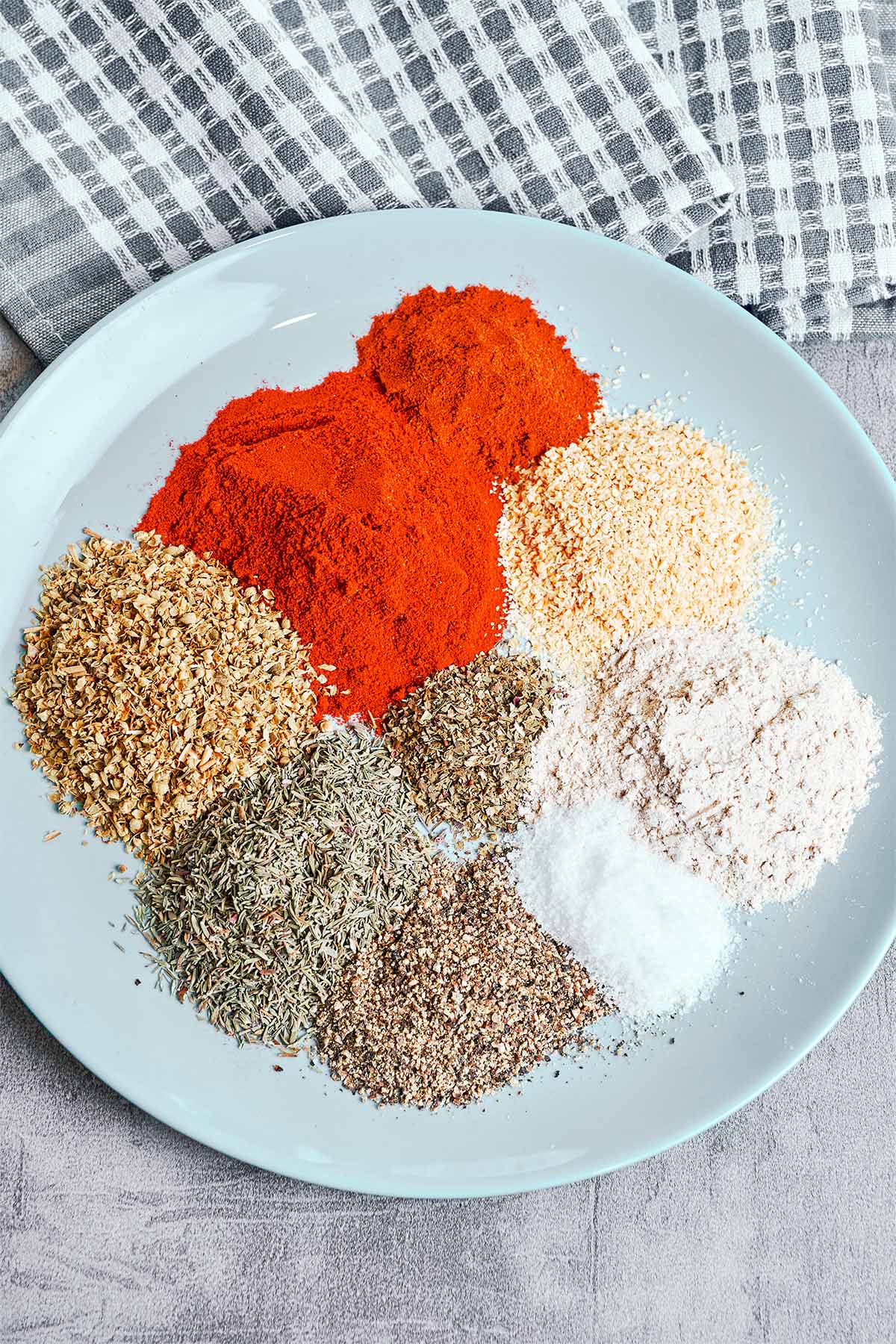 Fresh homemade Cajun seasoning spices arranged on a plate before mixing.