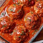 Juicy oven baked meatballs in rich homemade tomato sauce topped with fresh parsley