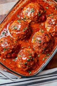 Juicy oven baked meatballs in rich homemade tomato sauce topped with fresh parsley