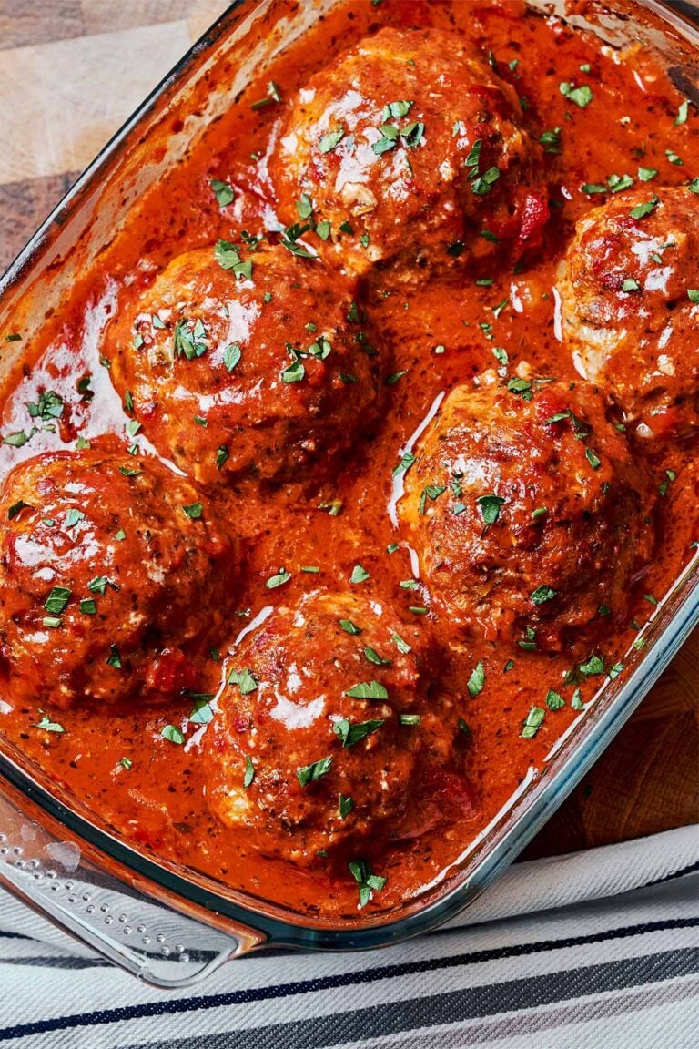 Juicy oven baked meatballs in rich homemade tomato sauce topped with fresh parsley