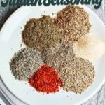 italian seasoning ingredients dried herbs and spices on white plate close up