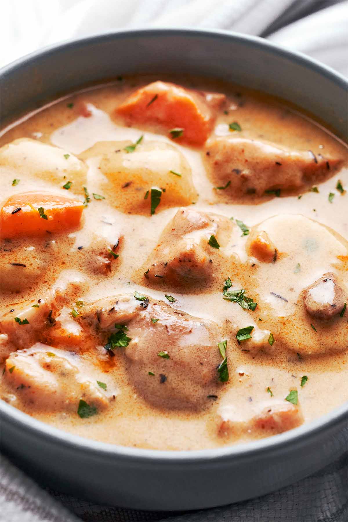 Creamy chicken cheddar potato chowder served in a bowl with tender chicken, potatoes, carrots, and fresh parsley