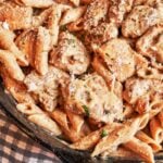Creamy chicken pasta in a skillet with golden chicken pieces, penne, grated Parmesan, and fresh parsley