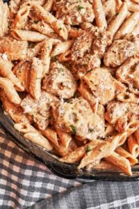 Creamy chicken pasta in a skillet with golden chicken pieces, penne, grated Parmesan, and fresh parsley