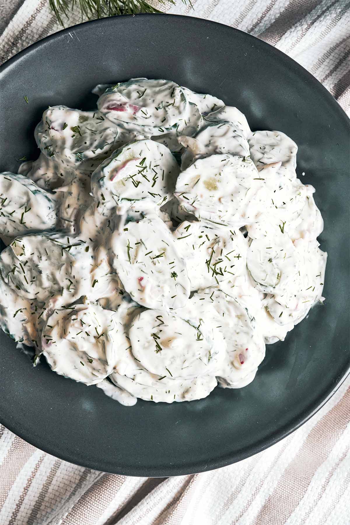Creamy cucumber salad with crisp cucumber slices, fresh dill, red onion, and sour cream dressing.