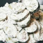 Creamy cucumber salad with crisp cucumber slices, fresh dill, red onion, and sour cream dressing on a spoon.