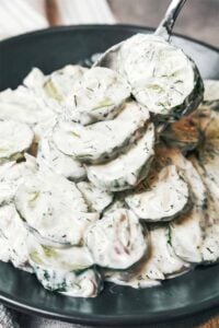 Creamy cucumber salad with crisp cucumber slices, fresh dill, red onion, and sour cream dressing on a spoon.