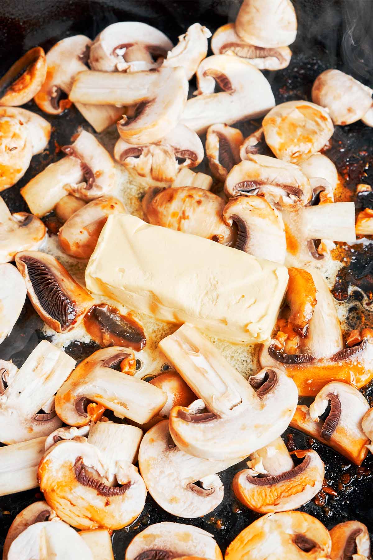 Sliced mushrooms melting into butter and chicken pan drippings for a rich creamy gnocchi sauce.