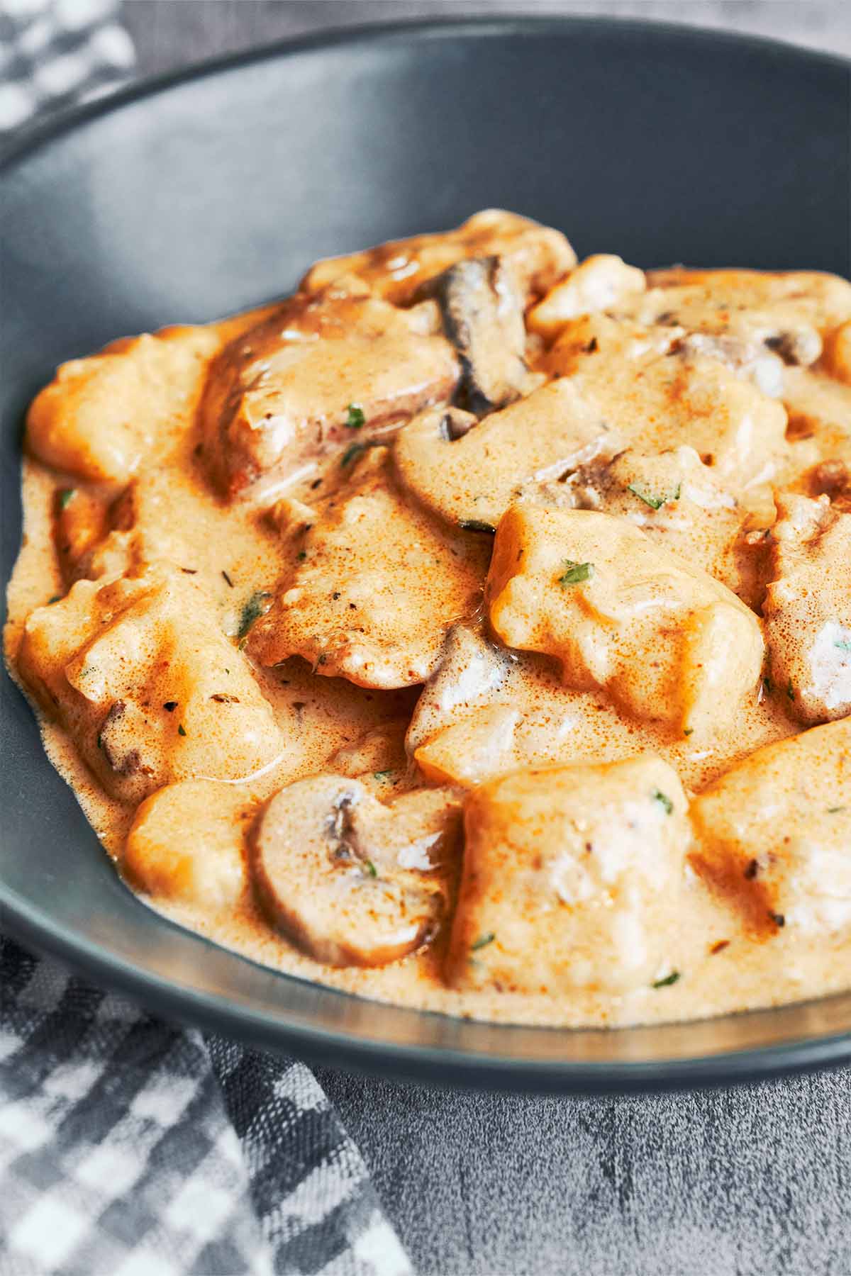 A bowl of Creamy Chicken and Gnocchi with tender chicken thighs, mushrooms, pillowy gnocchi, and garlic Parmesan cream sauce.