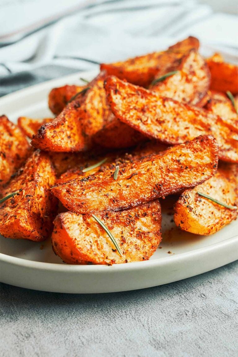 Crispy oven roasted potato wedges with deeply browned edges, smoky herb seasoning, and fresh rosemary