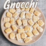 Fresh homemade gnocchi shaped with fork ridges and dusted with flour on a plate.
