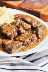 Beef Tips and Gravy with tender beef pieces in glossy brown gravy and mashed potatoes
