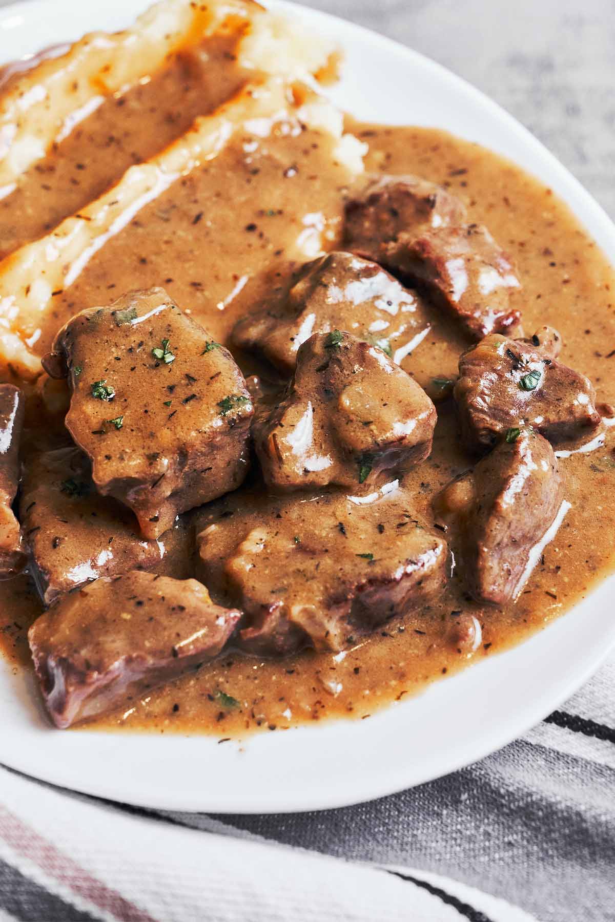 Tender beef pieces with glossy brown gravy served beside creamy mashed potatoes
