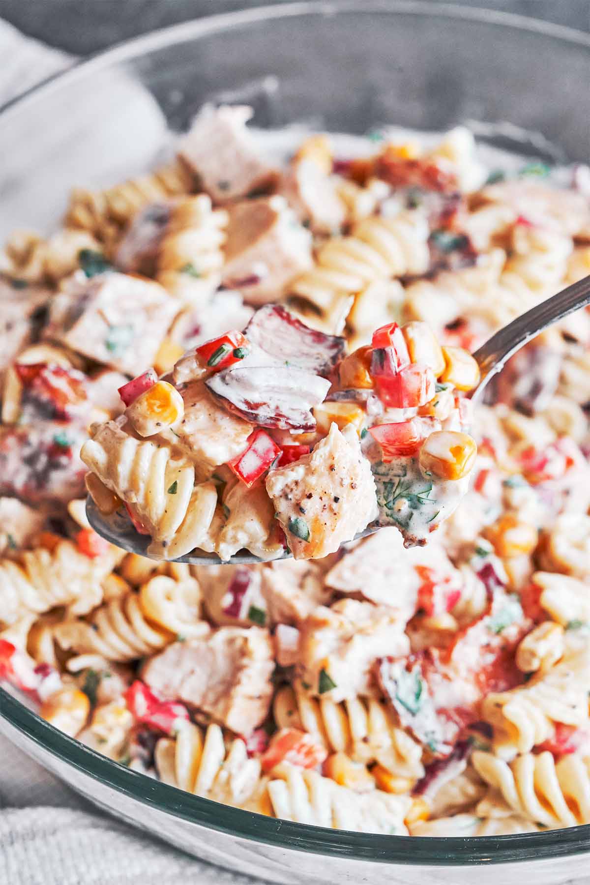 A generous spoonful of creamy fusilli with tender chicken, crisp bacon, sweet corn, and red pepper ready to serve
