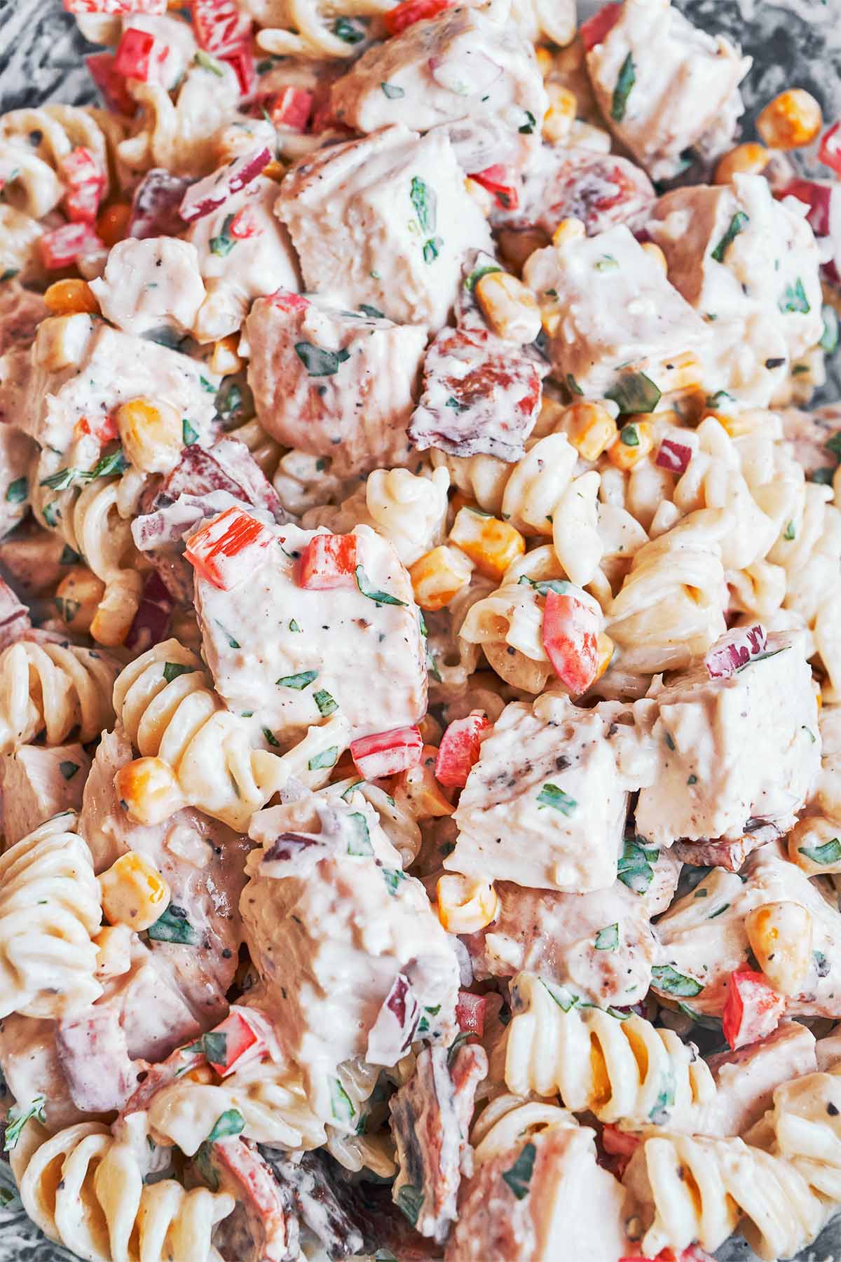 Close-up of creamy fusilli with tender chicken, smoky bacon, sweet corn, and little bites of red pepper throughout