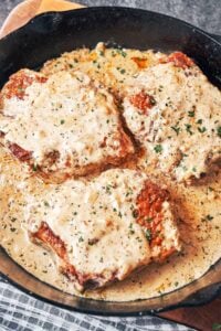 Creamy Dijon Pork Chops in a cast-iron skillet, covered in a rich mustard cream sauce and finished with parsley