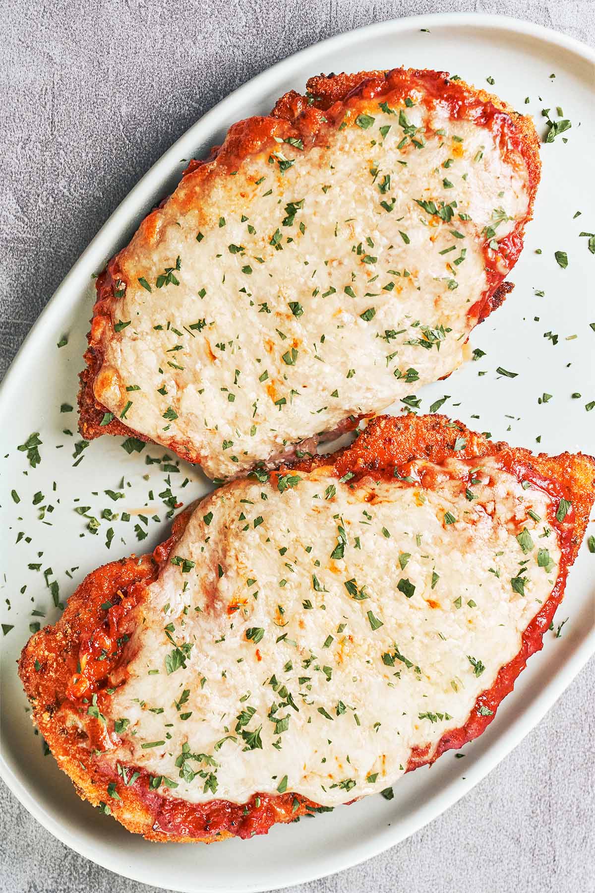 Crispy Chicken Parmesan topped with rich tomato sauce, melted mozzarella, and a sprinkle of fresh parsley.