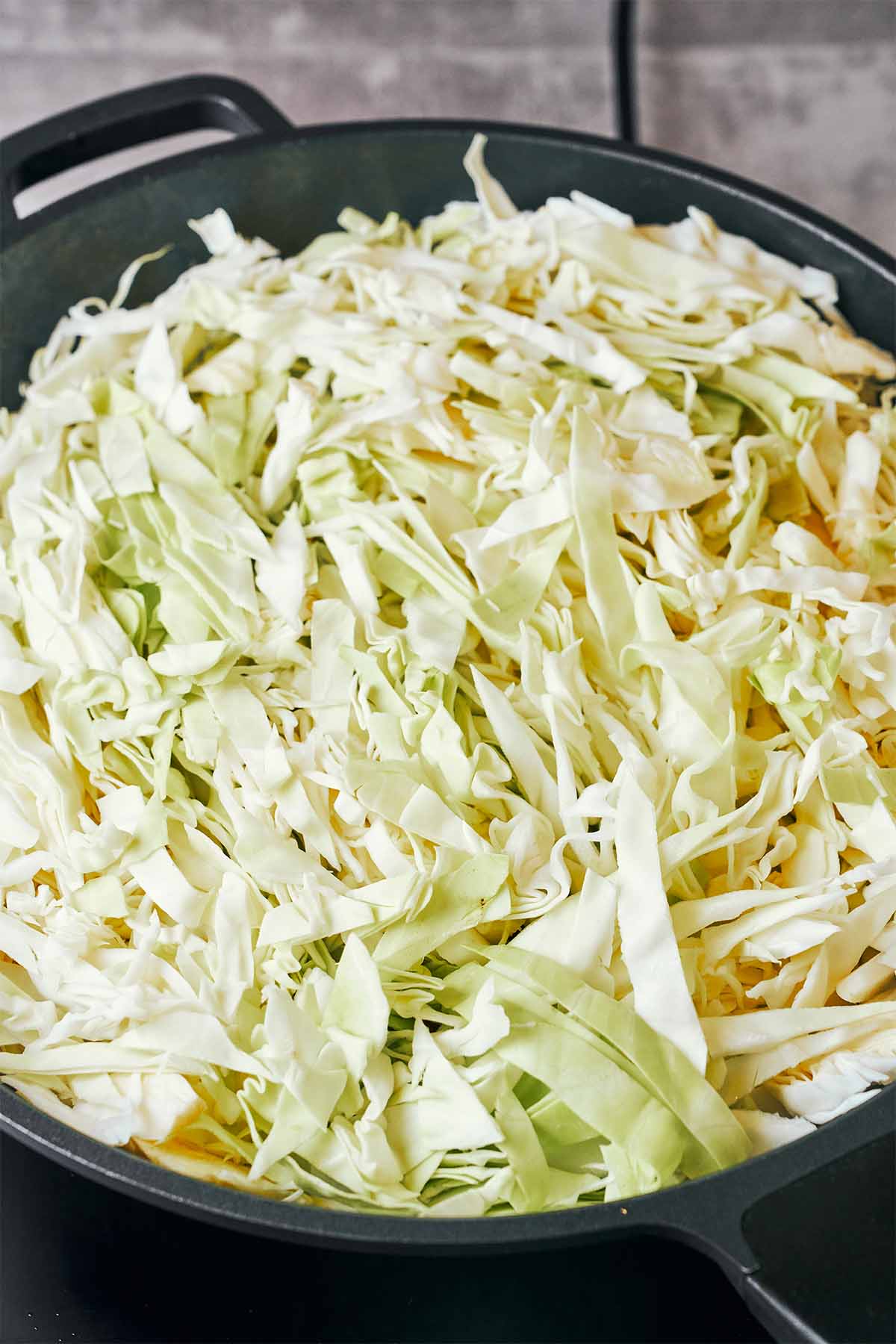 A generous pile of freshly shredded cabbage filling the wok before it cooks down.