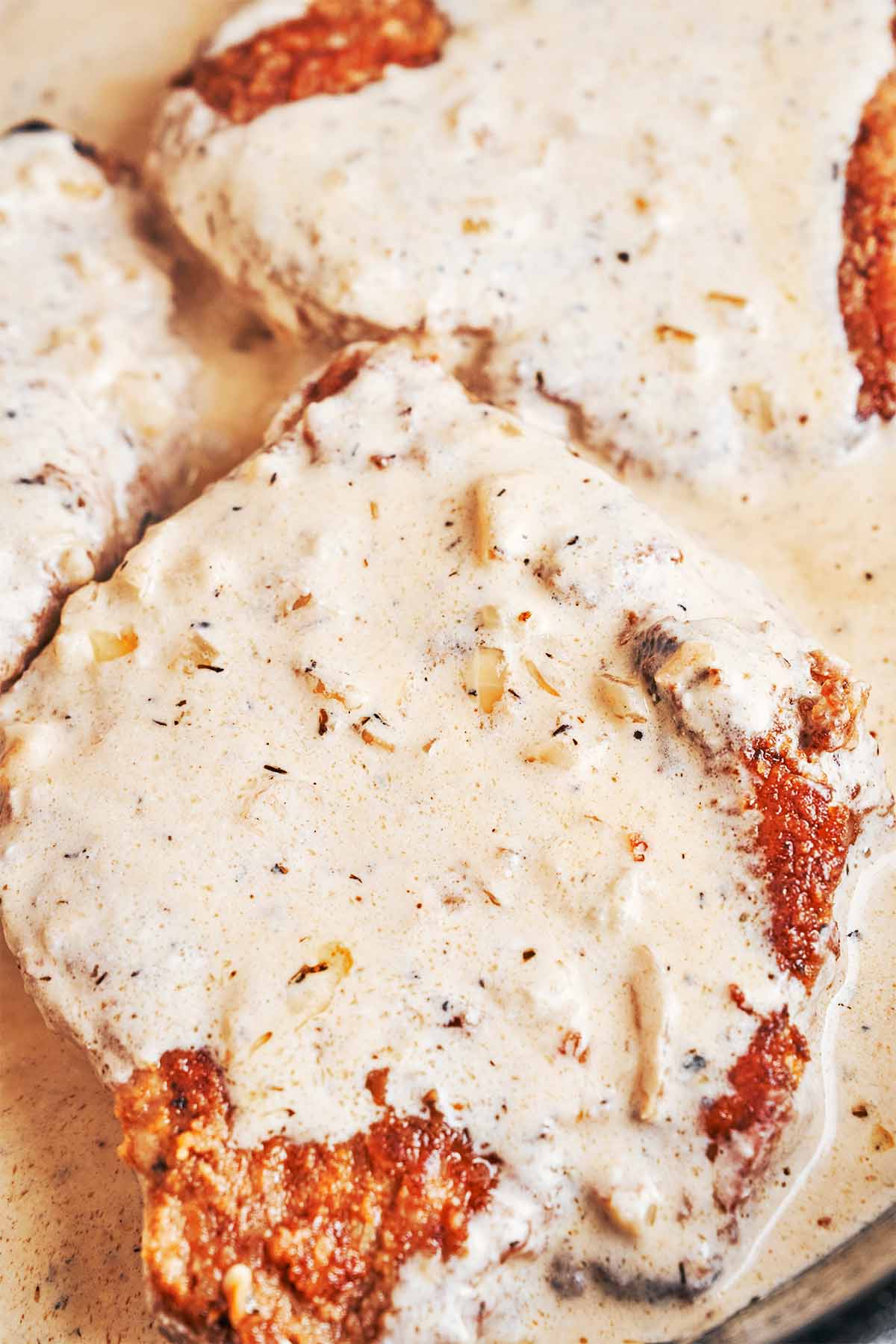 Golden pork chops nestled in the creamy Dijon sauce after gently simmering in the skillet