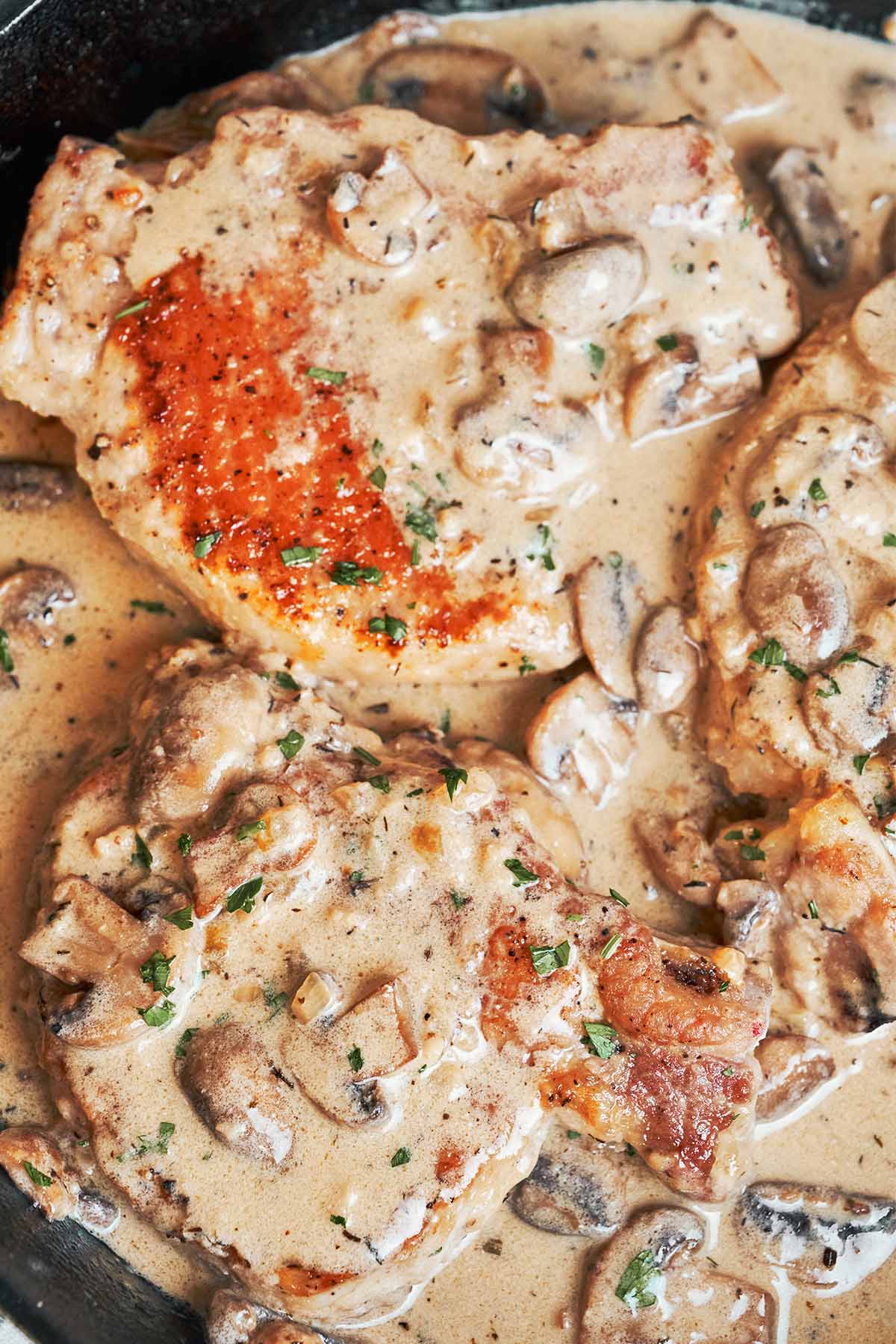 Golden pork chops nestled in creamy Pork Marsala sauce with browned mushrooms and a sprinkle of fresh parsley.