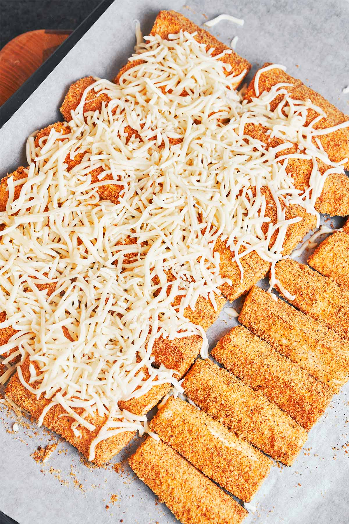 Baked zucchini wedges topped with plenty of shredded mozzarella, ready to go back in the oven until melted and golden.
