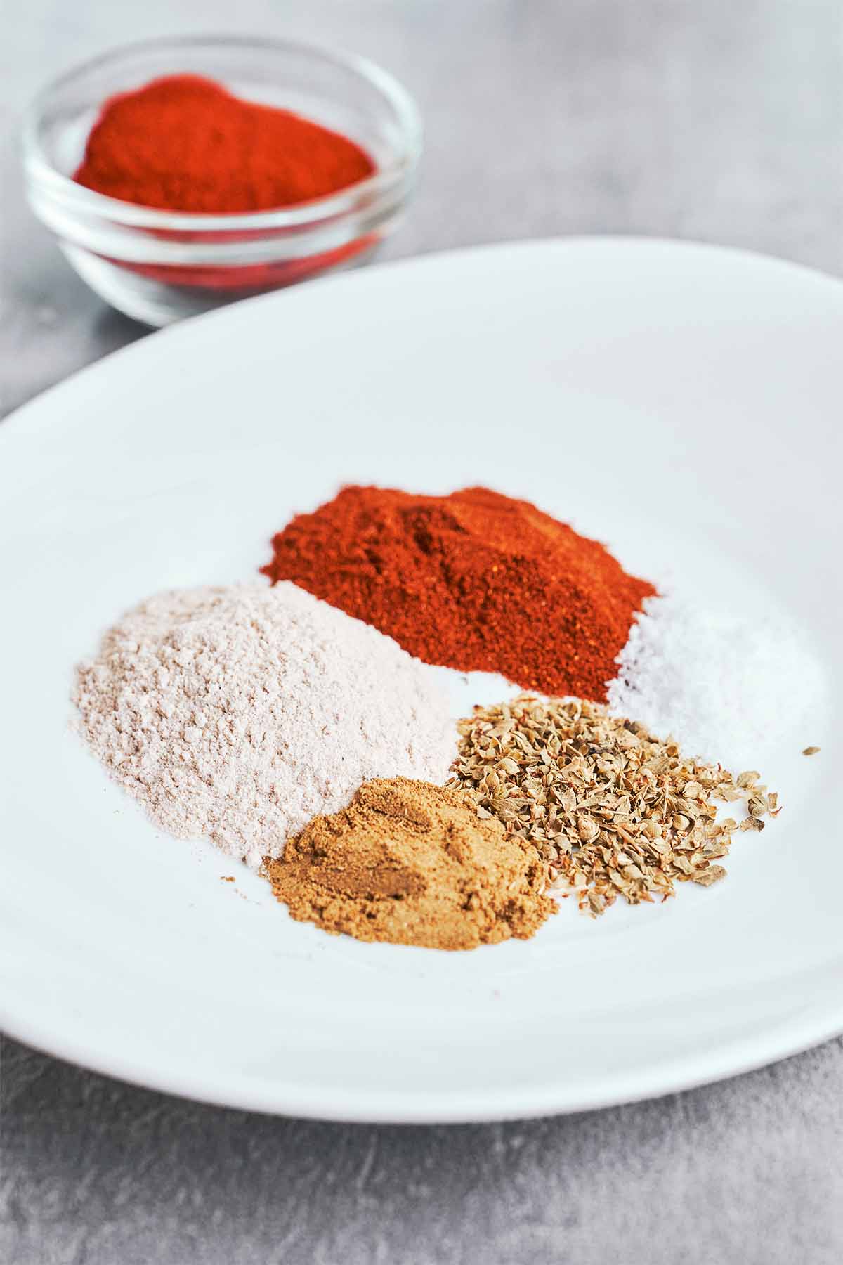 Chili powder, paprika, cumin, oregano, flour, and the remaining dry seasonings measured out and ready for the sauce.
