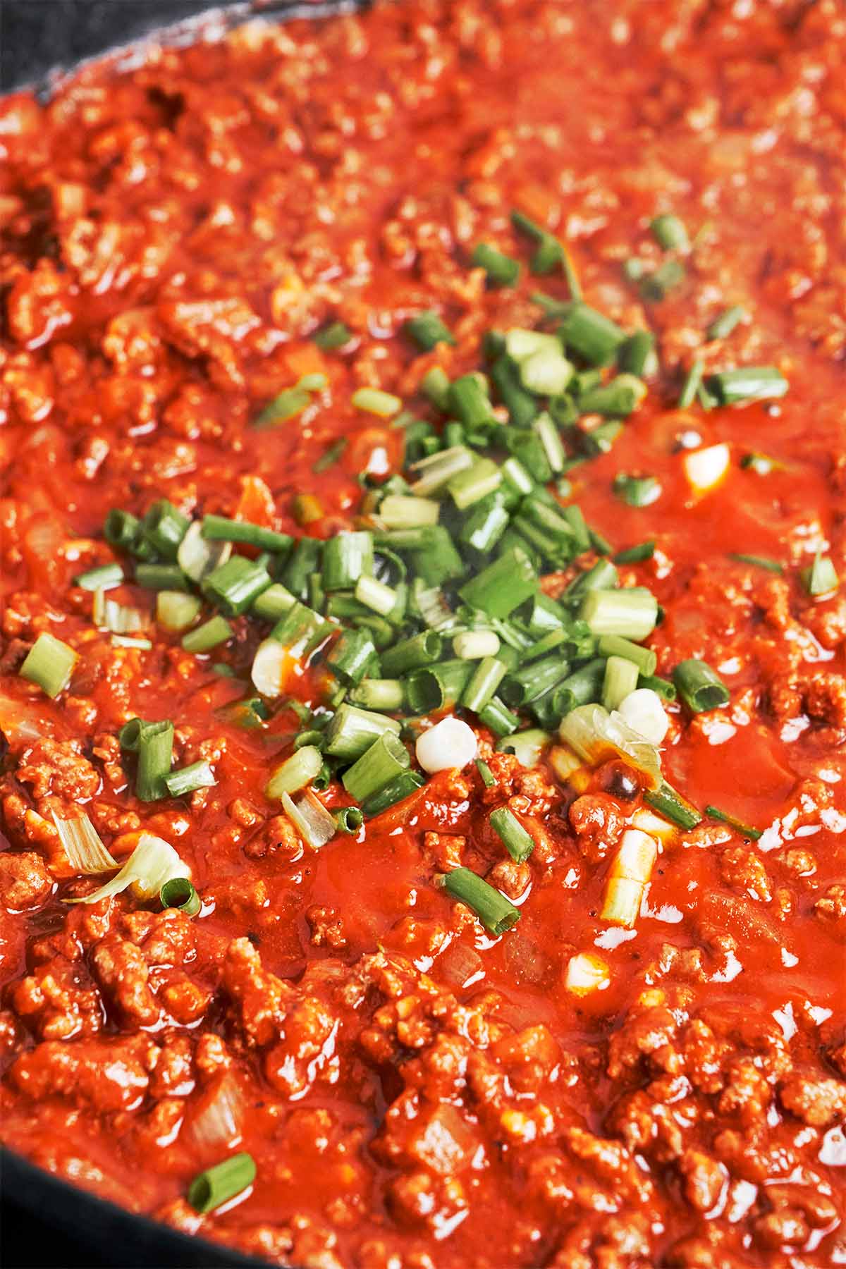 Chopped green onions stirred into the rich tomato beef sauce at the end for a fresh finish.