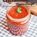 Homemade enchilada sauce served in a glass jar with warm red chile spices and a smooth, silky texture.