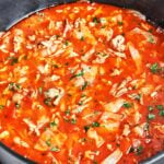 Cabbage roll soup with ground beef and rice in a deep pot, filled with tender cabbage and carrots in tomato broth and sprinkled with fresh parsley.