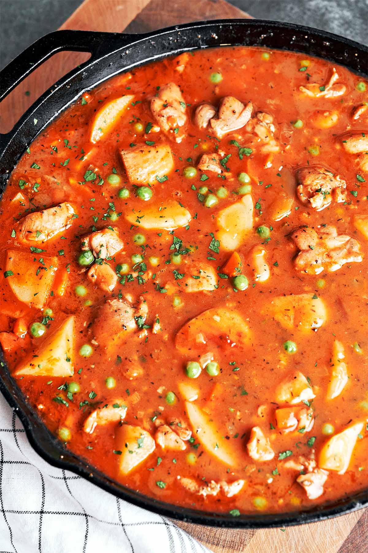 Finished chicken stew with tender potatoes, juicy chicken, peas, and parsley in a rich, savory sauce.