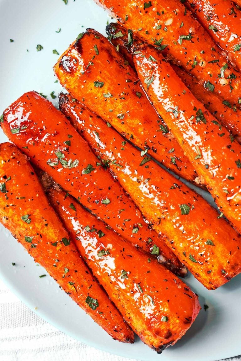 Honey garlic butter roasted carrots with caramelized edges, glossy glaze, and a sprinkle of fresh herbs