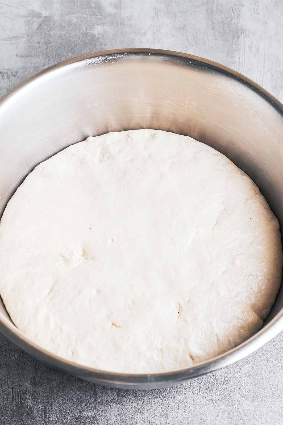 The dough after its first rise, looking soft, puffy, and ready to shape