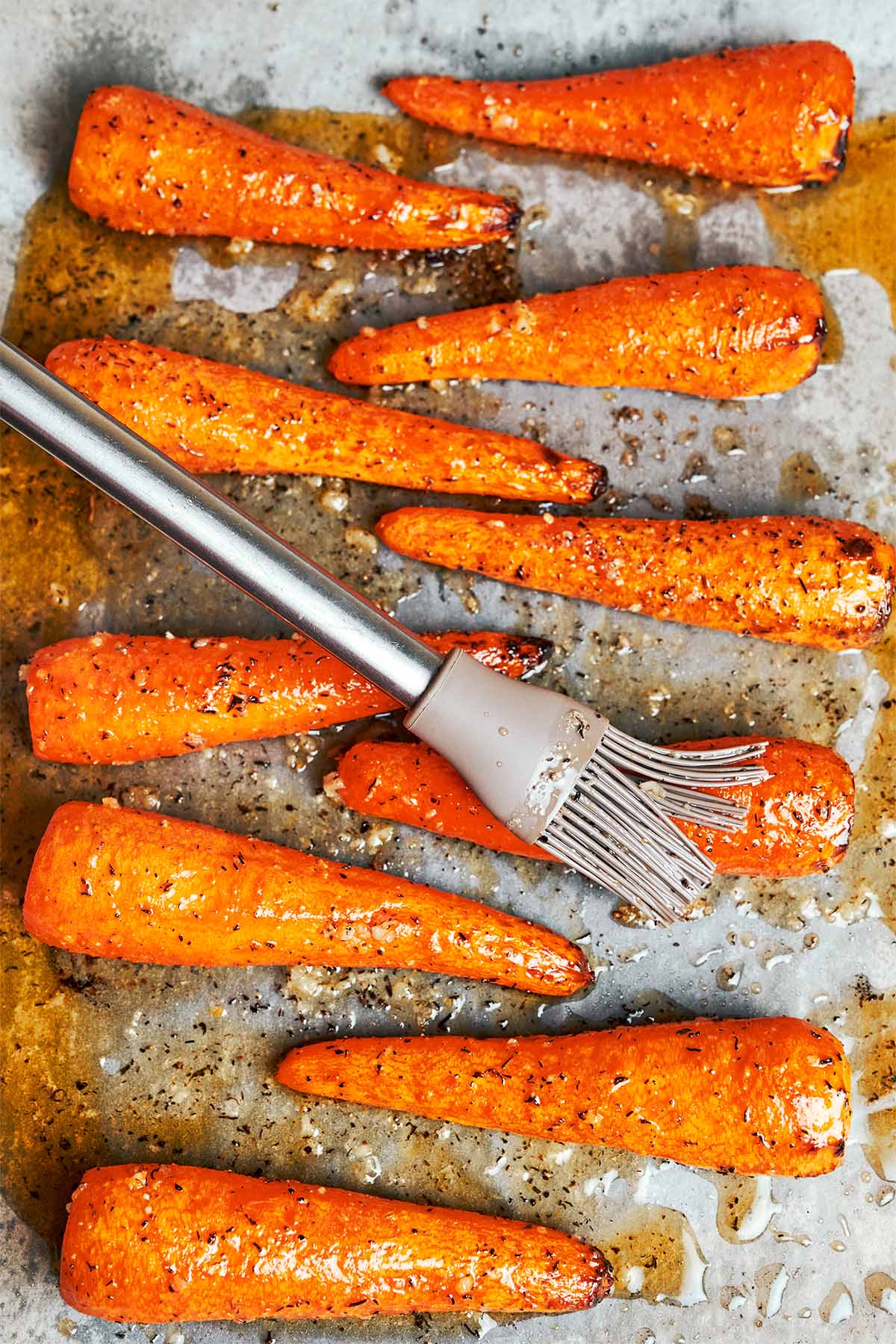 Brushing the warm honey garlic butter glaze over the roasted carrots before they go back into the oven