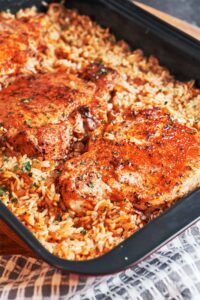 Baked Pork Chops and Rice with juicy golden pork chops over savory, fluffy rice finished with fresh parsley.
