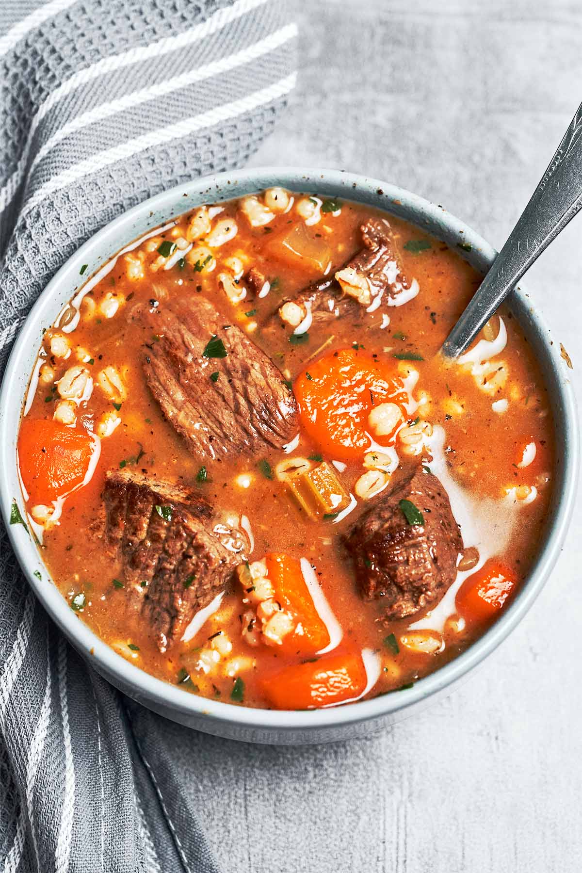 Tender beef and barley ladled into a warm bowl with carrots, herbs, and plenty of rich savory broth