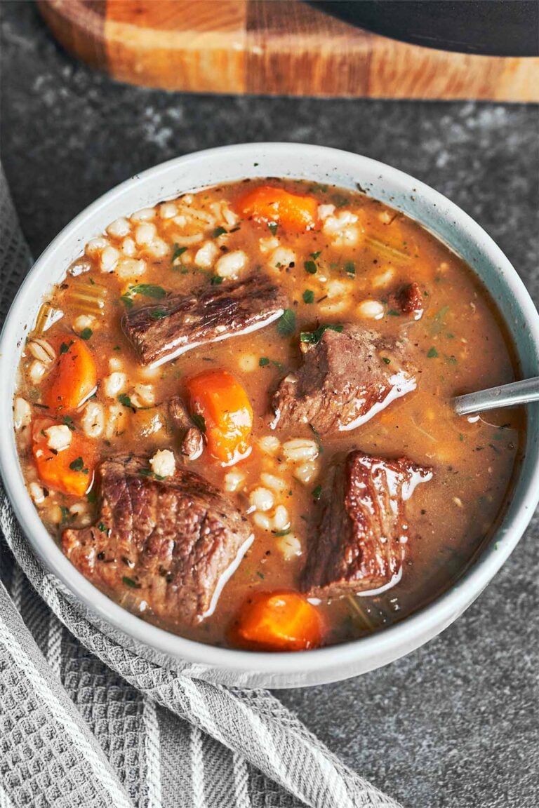 Beef barley soup served in a warm bowl with tender beef, chewy pearl barley, carrots, and a rich savory broth