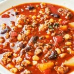 A cozy bowl of homemade Cowboy Soup, loaded with savory ground beef, tender potatoes, pinto and kidney beans, sweet corn, and red bell pepper in a rich, smoky tomato broth, finished with fresh parsley.
