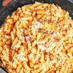 Creamy pumpkin pasta with bacon, tender fusilli, and a sprinkle of Parmesan, ready to serve from a cast iron skillet.
