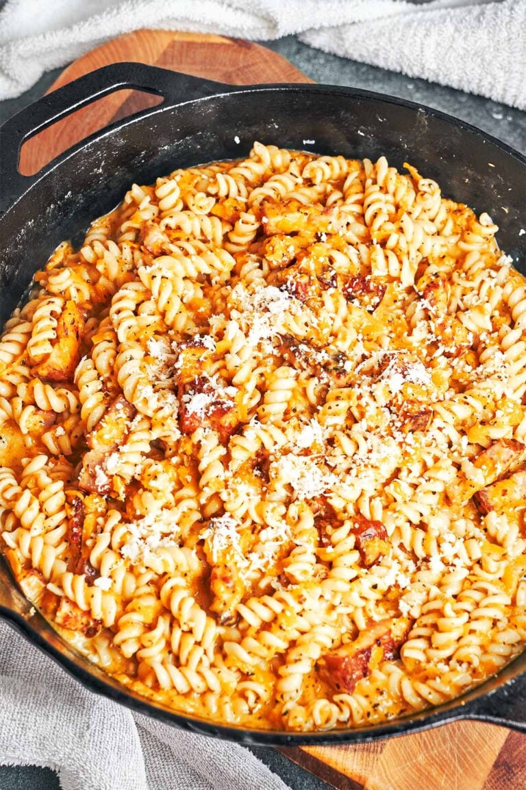 Creamy pumpkin pasta with bacon, tender fusilli, and a sprinkle of Parmesan, ready to serve from a cast iron skillet.