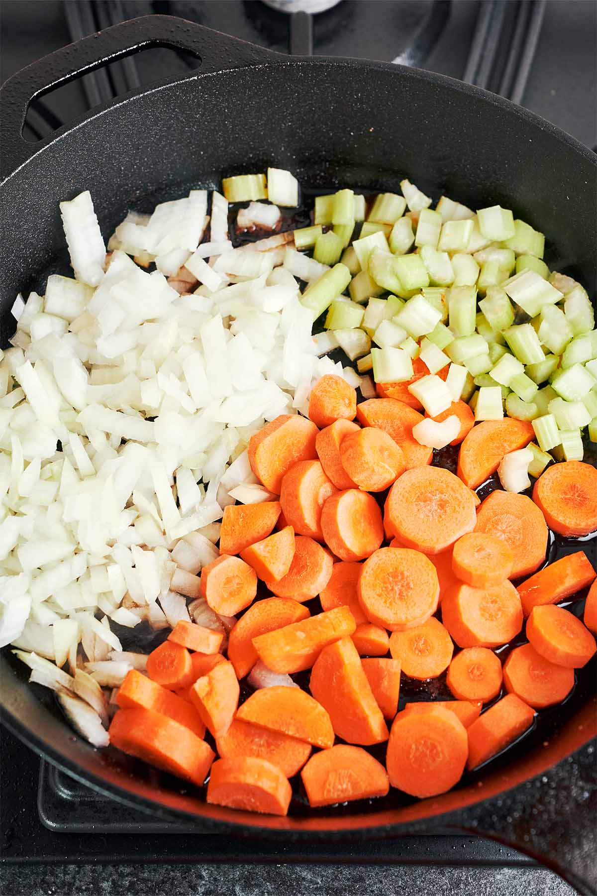 Onion, carrots, and celery going into the skillet to build the savory base for the soup