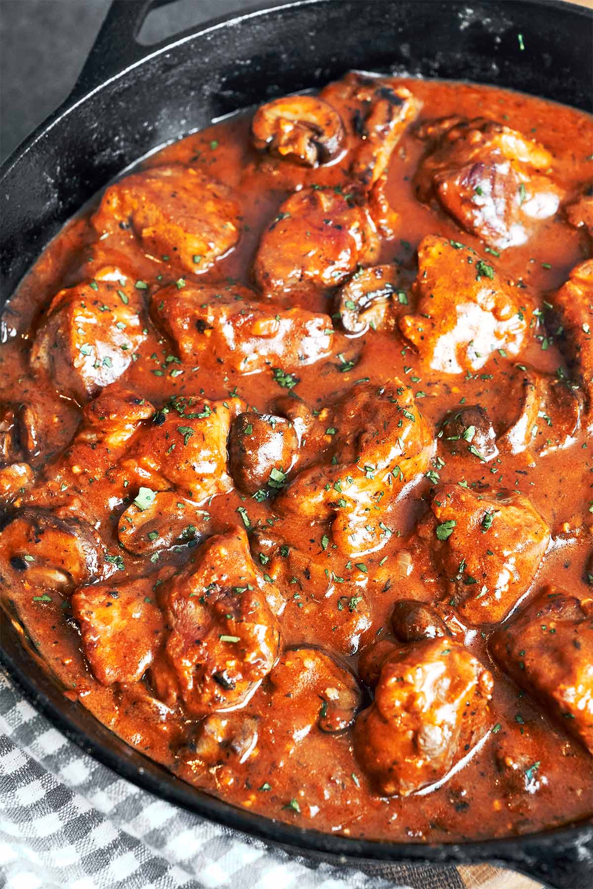 Tender chunks of pork and browned mushrooms tucked into glossy gravy, finished with chopped parsley in the skillet.