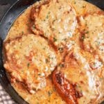 Smothered pork chops in rich onion gravy, finished with fresh parsley in a cast-iron skillet.